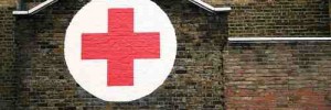 A red cross painted in a white circle on the side of a house in Dalston