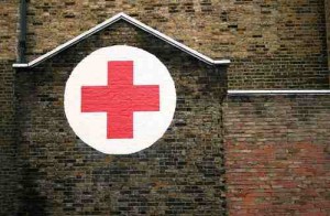 A red cross painted in a white circle on the side of a house in Dalston