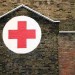 A red cross painted in a white circle on the side of a house in Dalston