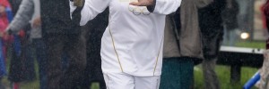 Sally Gunnell carries the Olympic Flame on the Torch Relay leg through a wet Portsmouth on Monday / photo LOCOG