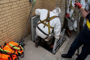 Wearing a safety harness a sewer worker prepares to descend. Note the orange bags - these contain emergency oxygen supplies and must be carried by all visitors.